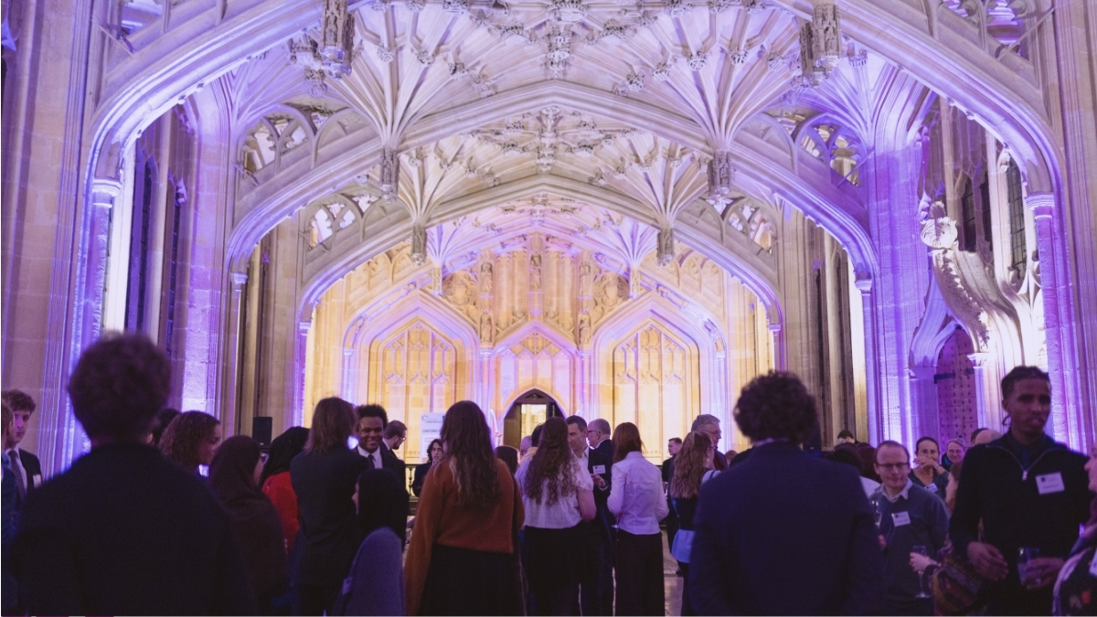Picture of a crowd of guests inside the Divinity School, bathed in purple light