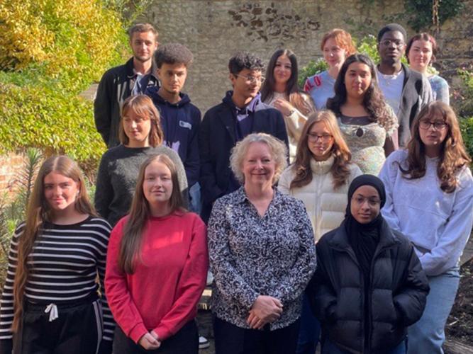 Group photo taken in an outdoor garden setting with stone walls and greenery in the background. The image shows new Astrophoria Foundation Year students for the 2025/26 cohort standing on wooden steps alongside Dr Alison MacDonald, under a clear blue sky.