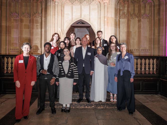 Group portrait taken in the Divinity School, Oxford. The Vice-Chancellor of Oxford stands on the far left wearing a red suit, and the Chancellor stands at the centre in a dark suit. At the right is the Director of the Astrophoria Foundation Year